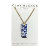 Necklace with a blue floral pendant on a Clay Blanca Ceramics card.