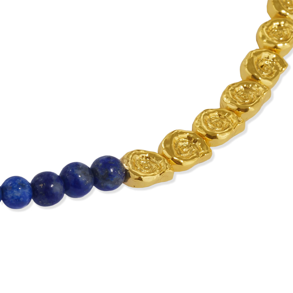 A close-up of a beaded necklace featuring four polished round lapis lazuli blue beads connected to a strand of textured, organic-shaped gold links on a plain white background.