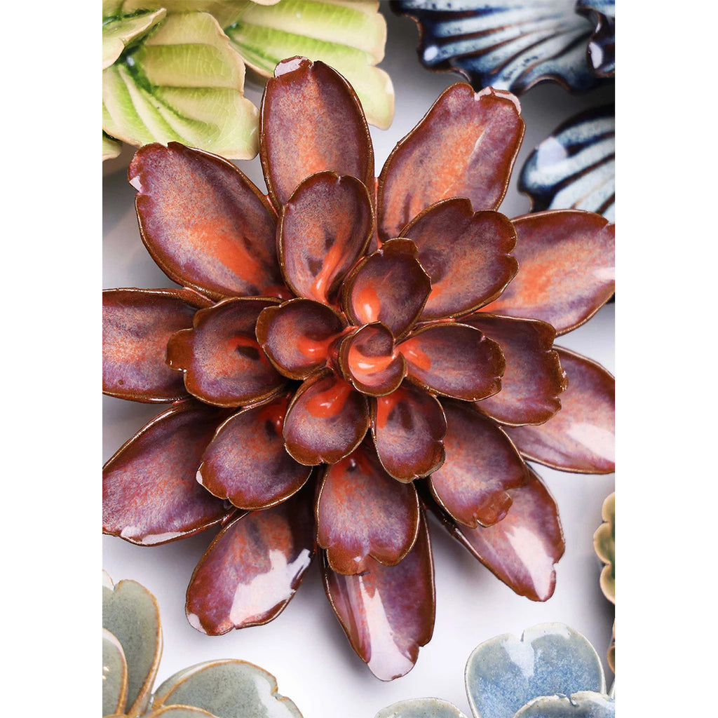 Close-up of a ceramic succulent plant with a glossy finish on a white background.
