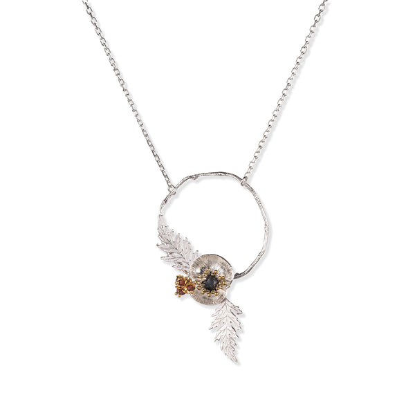 Necklace with a circular pendant featuring poppy leaves and a small gemstone beads on a white background