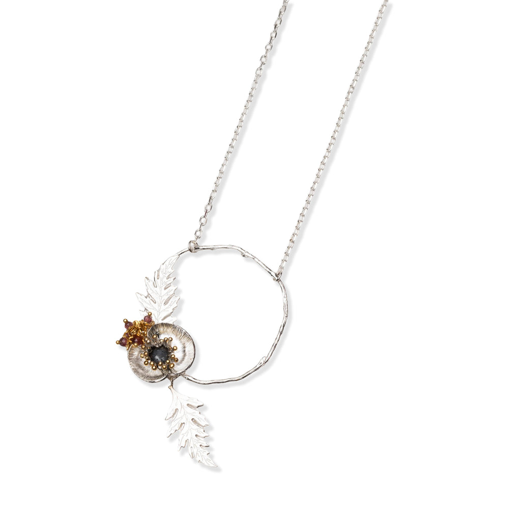 Necklace with a circular pendant featuring poppy leaves and a small gemstone beads on a white background