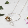 Necklace with a circular pendant featuring poppy leaves and a small gemstone beads on a light background with plant leaves.