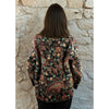 Person wearing a patterned quilted jacket against a stone wall