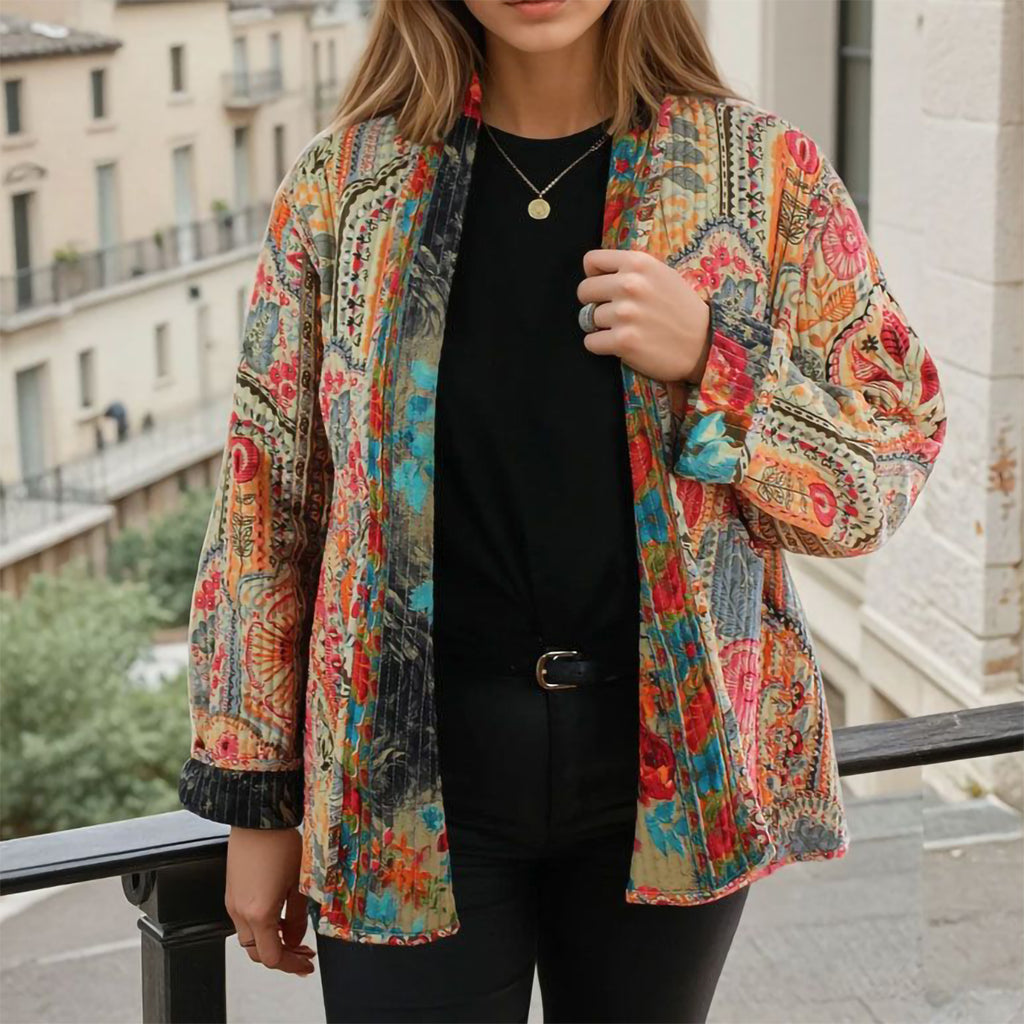 Person wearing a colorful patterned jacket outdoors with buildings in the background