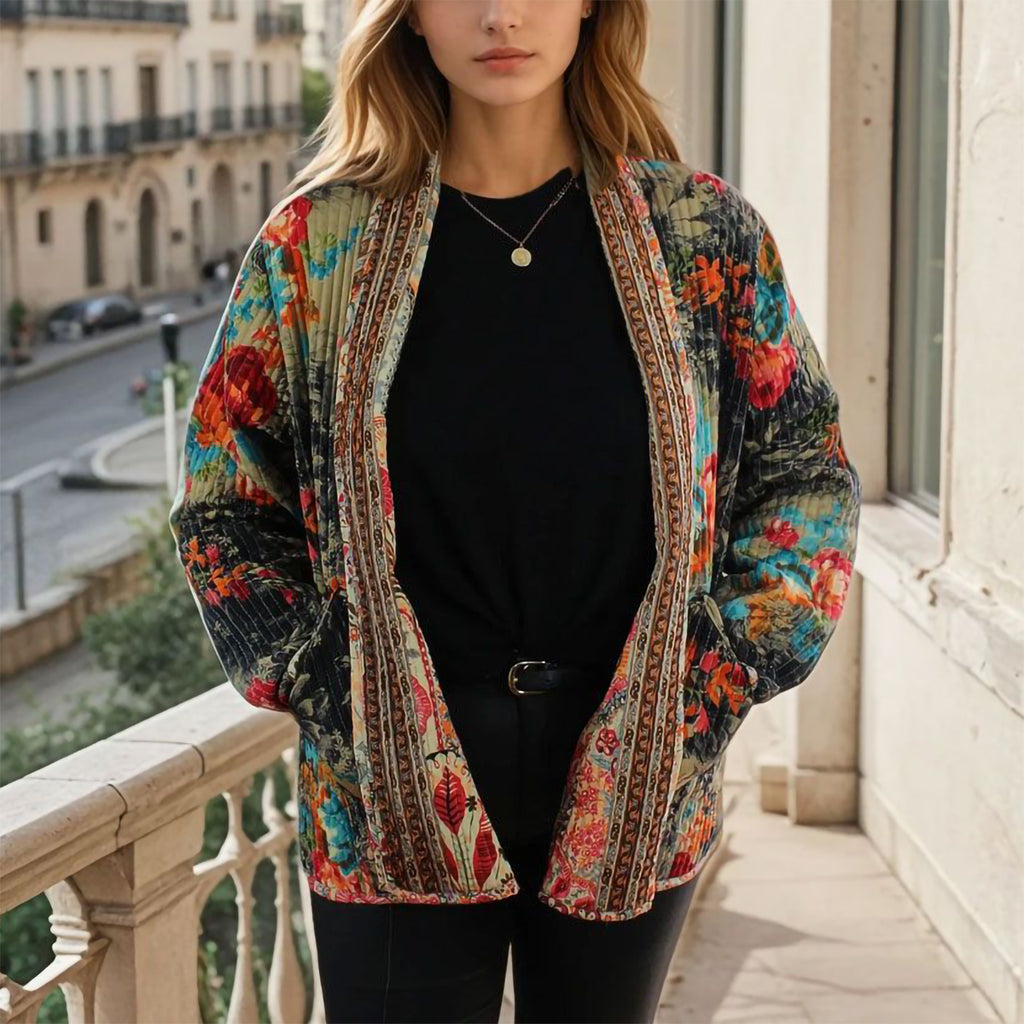 Woman wearing a colorful patterned jacket on a balcony with a cityscape background