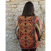 Person wearing a patterned jacket standing against a stone wall