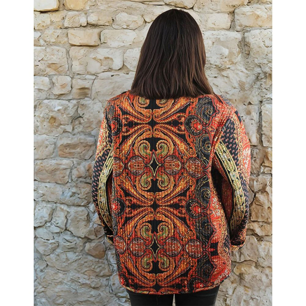 Person wearing a patterned jacket standing against a stone wall