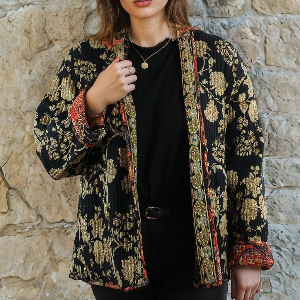 Person wearing a patterned jacket against a stone wall