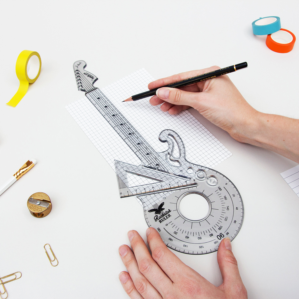 Guitar-shaped protractor with a hand holding a pencil on a white background