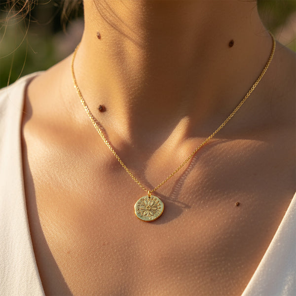 Close-up of a person wearing a gold necklace with a round pendant.
