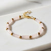 Bracelet with pink beads and gold accents on a white surface