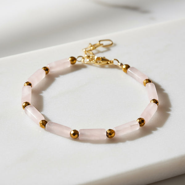Bracelet with pink beads and gold accents on a white surface