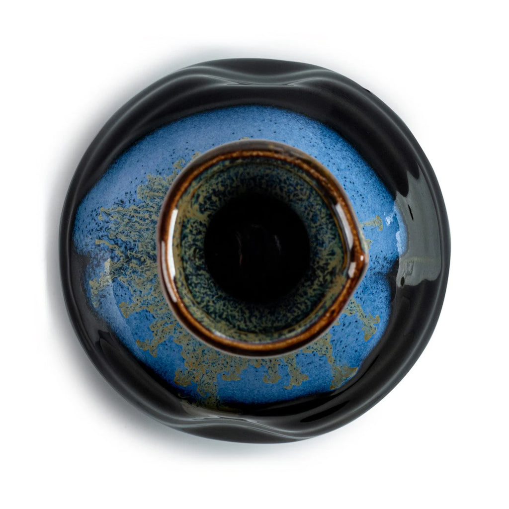 Overhead view of ceramic sake bottle with blue and black gradient on a white background