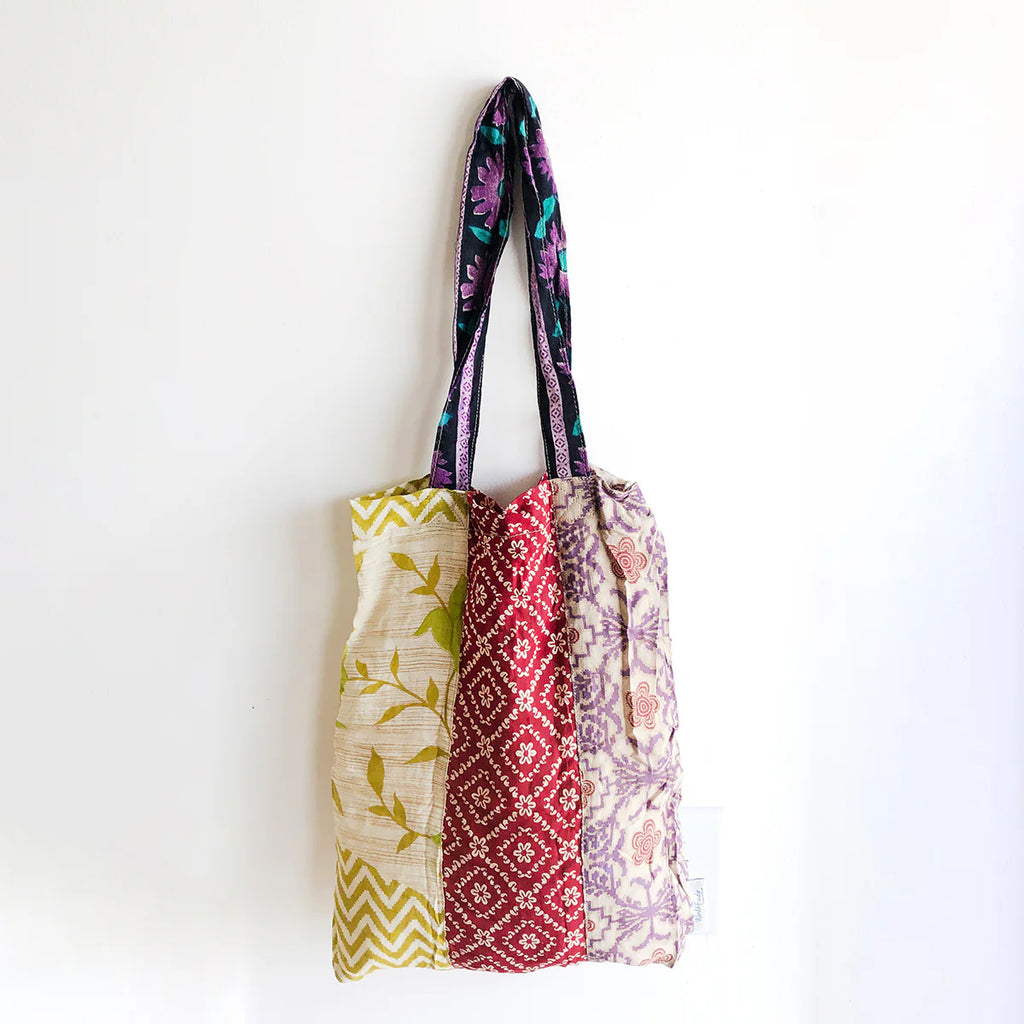 Colourful patchwork tote bag with patterned handle on a white background