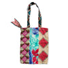 Colourful patchwork tote bag with patterned handle on a white background