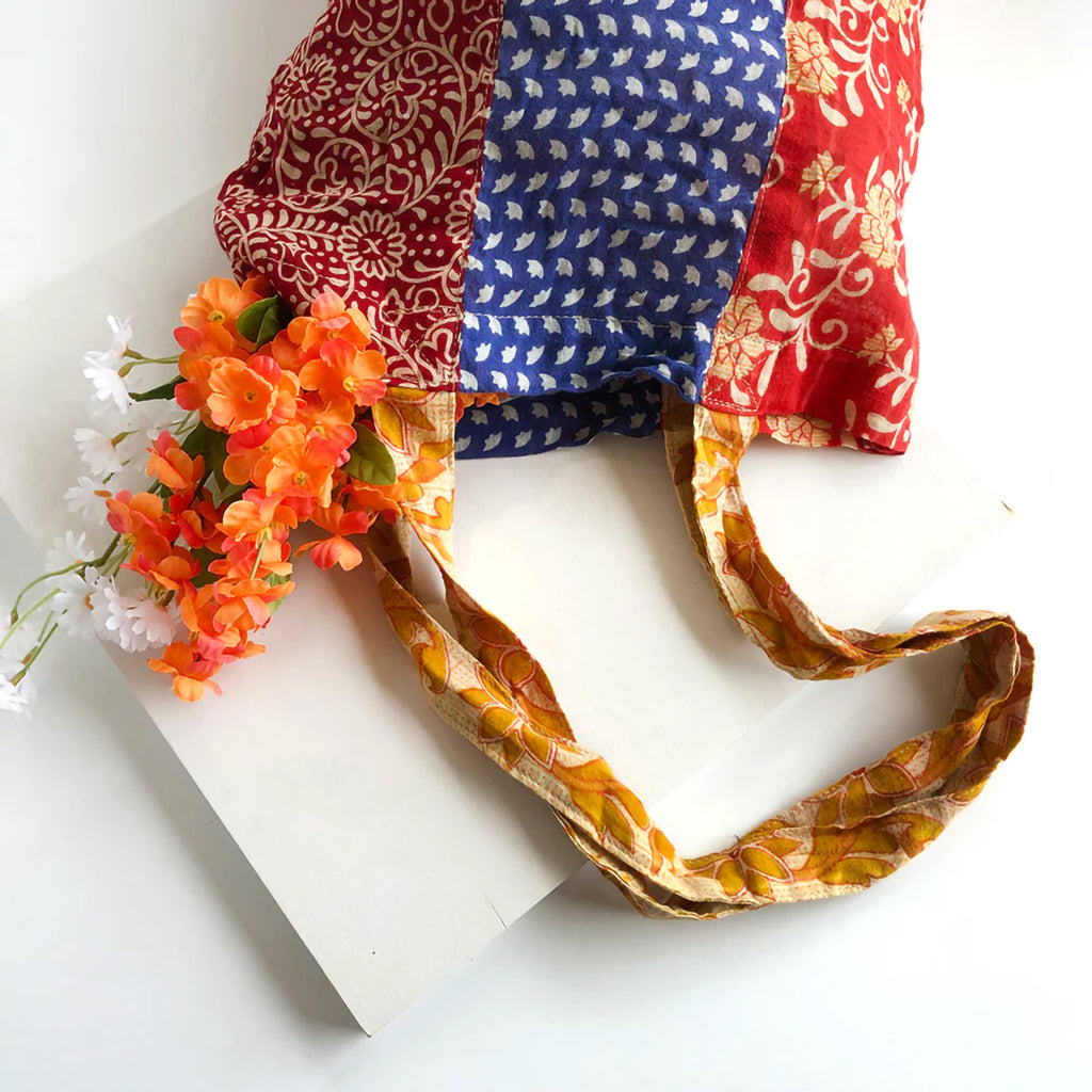 Colourful patchwork tote bag with patterned handle on a white background with flowers