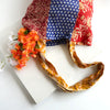 Colourful patchwork tote bag with patterned handle on a white background with flowers