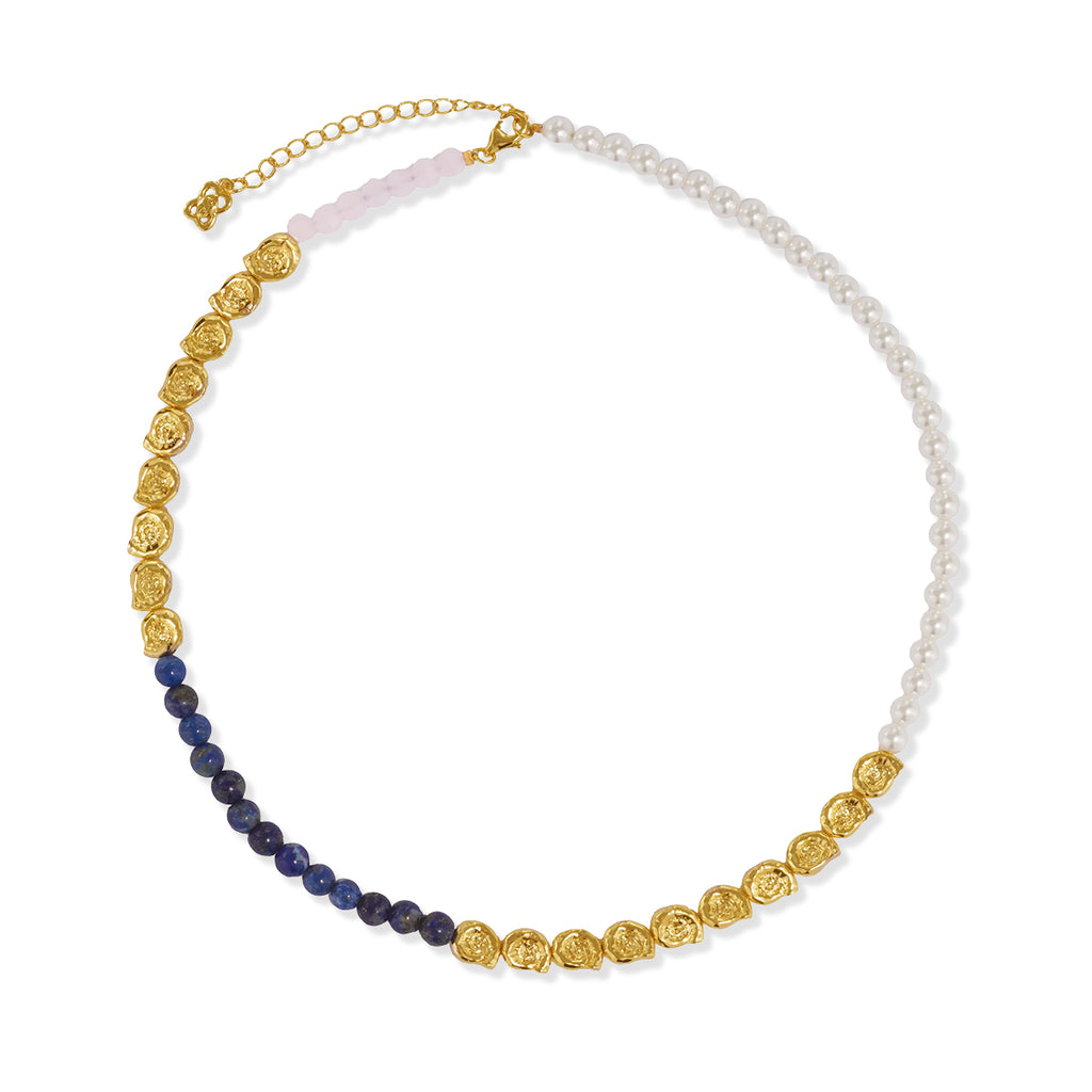 A gold-plated beaded necklace featuring a white pearl strand, a light pink bead section, and dark blue lapis lazuli beads, all connected by textured gold links, shown on a white background.
