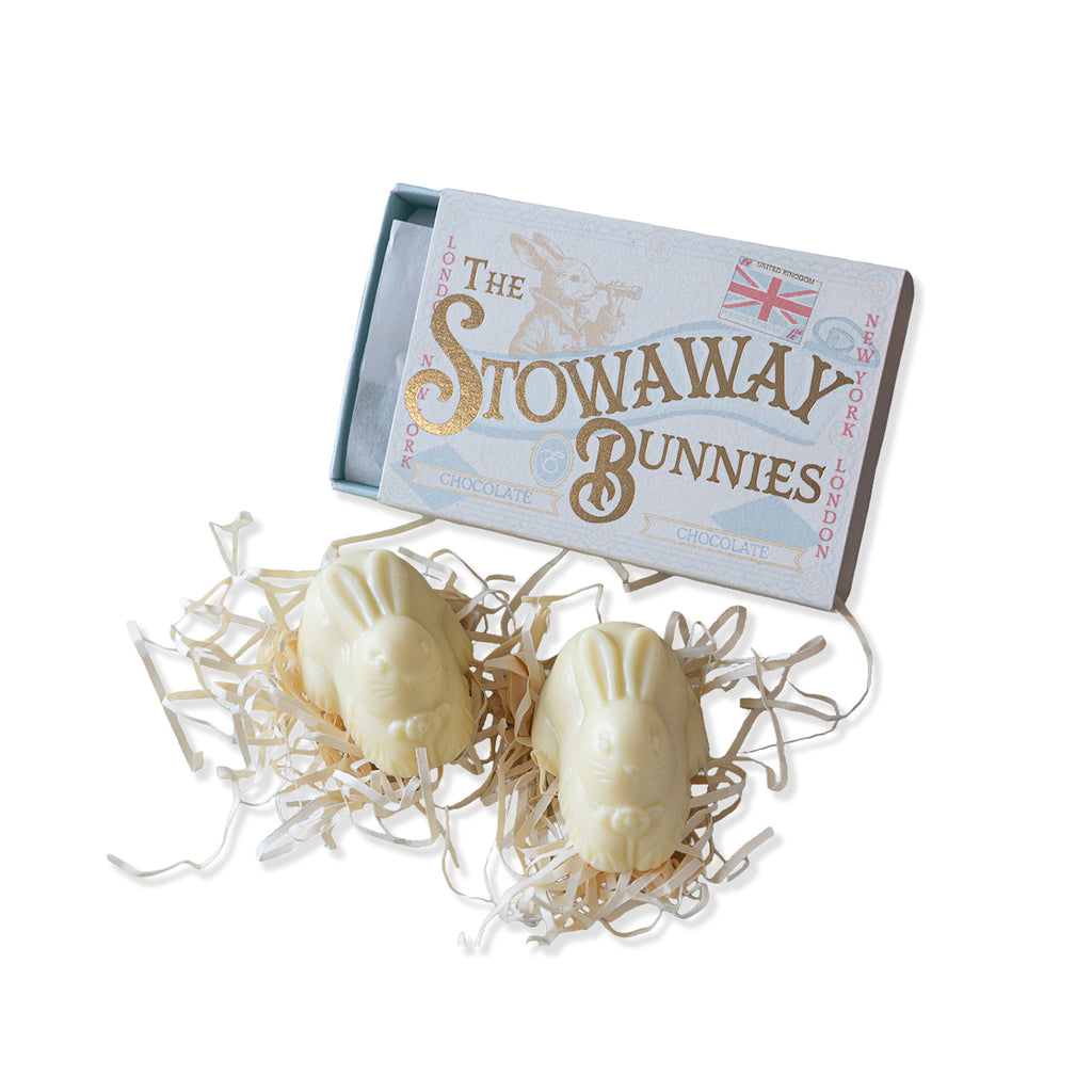 Two white chocolate bunnies with a box labeled 'The Stowaway Bunnies' on a white background.