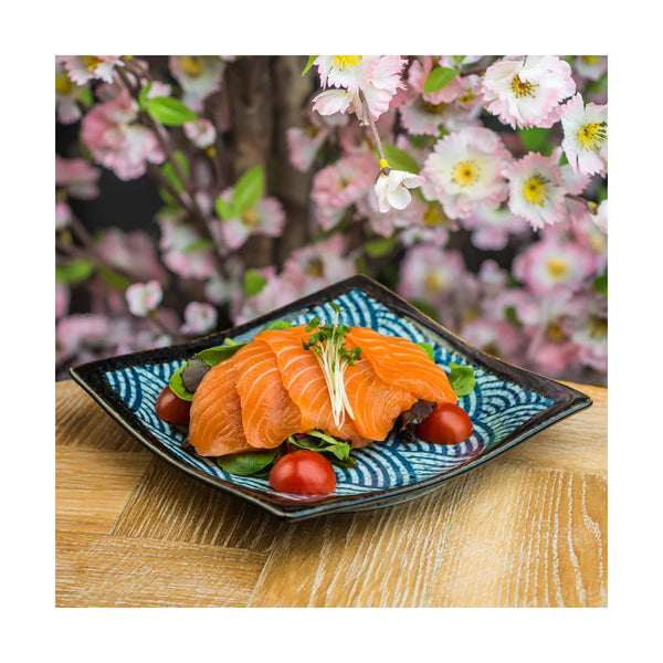 Sashimi on a decorative plate with cherry blossoms in the background