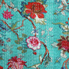 Floral patterned fabric with red, pink, and green flowers on a turquoise background