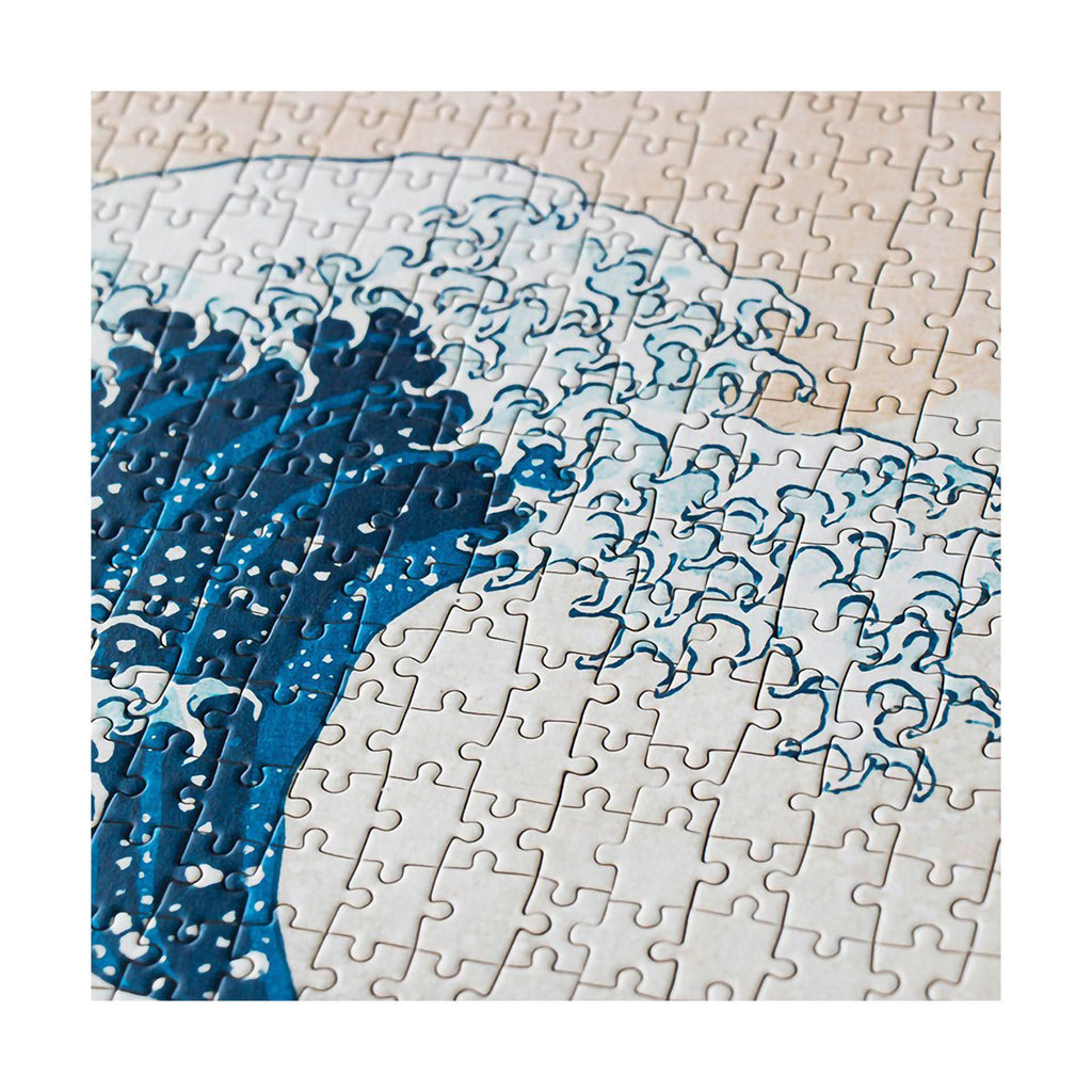 Close up detail image of jigsaw puzzle with a blue wave design on a beige background