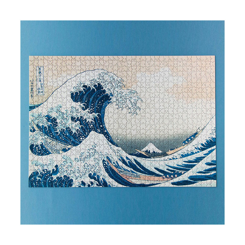 Jigsaw puzzle with a design of a large wave and mountain, framed by a blue border.