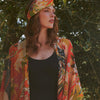Model wearing cranes and eucalyptus fans pattern throwover with matching bandana against summer olive trees background.