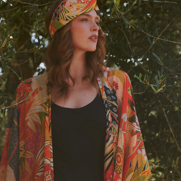 Model wearing cranes and eucalyptus fans pattern throwover with matching bandana against summer olive trees background.
