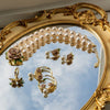 Gold and pearl jewelry set with floral details on a decorative mirror.