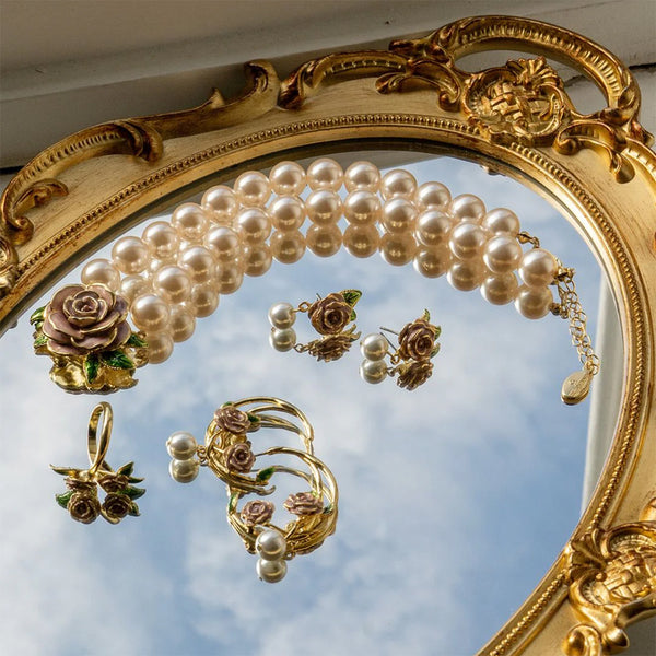 Gold and pearl jewelry set with floral details on a decorative mirror.