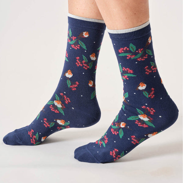 Navy socks with holly and robin pattern worn by a person on a light gray background