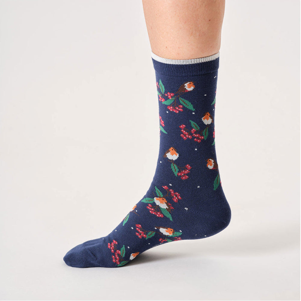 Navy sock with colourful Christmas robin and leaf pattern worn by a person on a white background