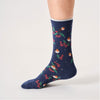 Navy sock with colourful Christmas robin and leaf pattern worn by a person on a white background