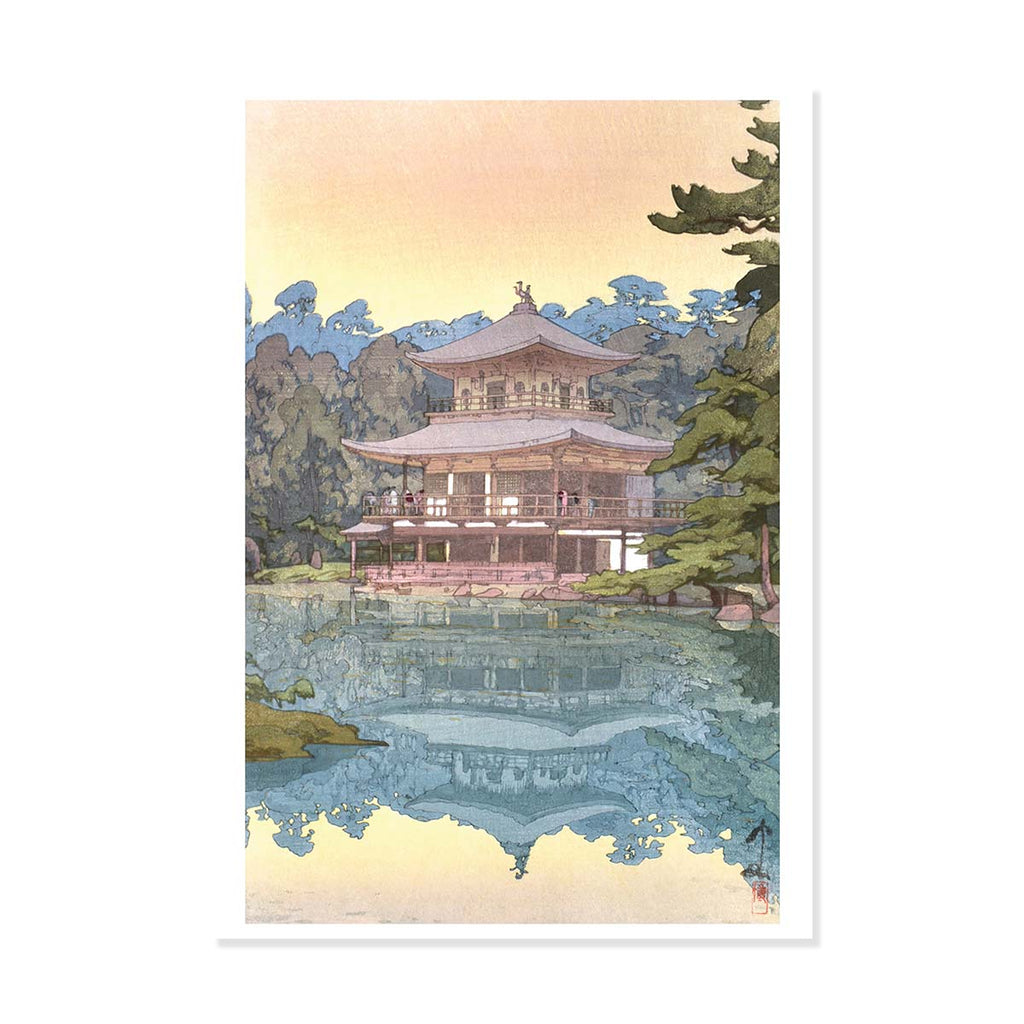 Traditional Japanese building reflected in water with trees in the background