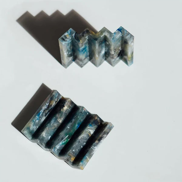 Two deep blue marble effect recycled plastic soap dishes with zig zag design on a plain light grey background.