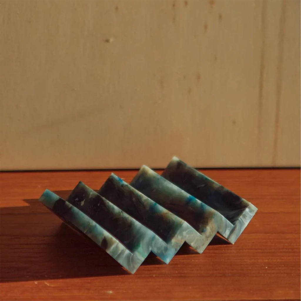 Deep blue marble effect recycled plastic soap dish with zig zag design on a wooden table background.