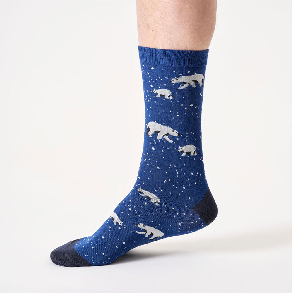 Blue sock with white polar bear pattern worn by a person on a white background