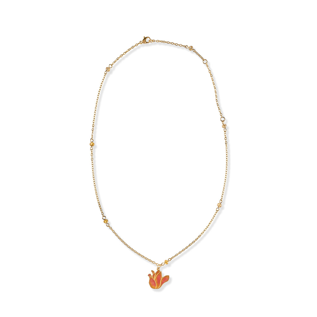 Gold tone necklace with amber beads and pendant shaped like tulip flower on a white background. 