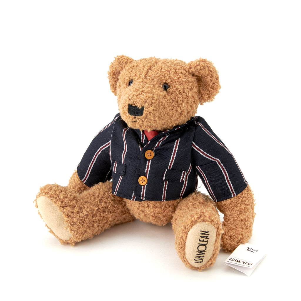 A plush teddy bear with a striped blue and red blazer and a bow tie.